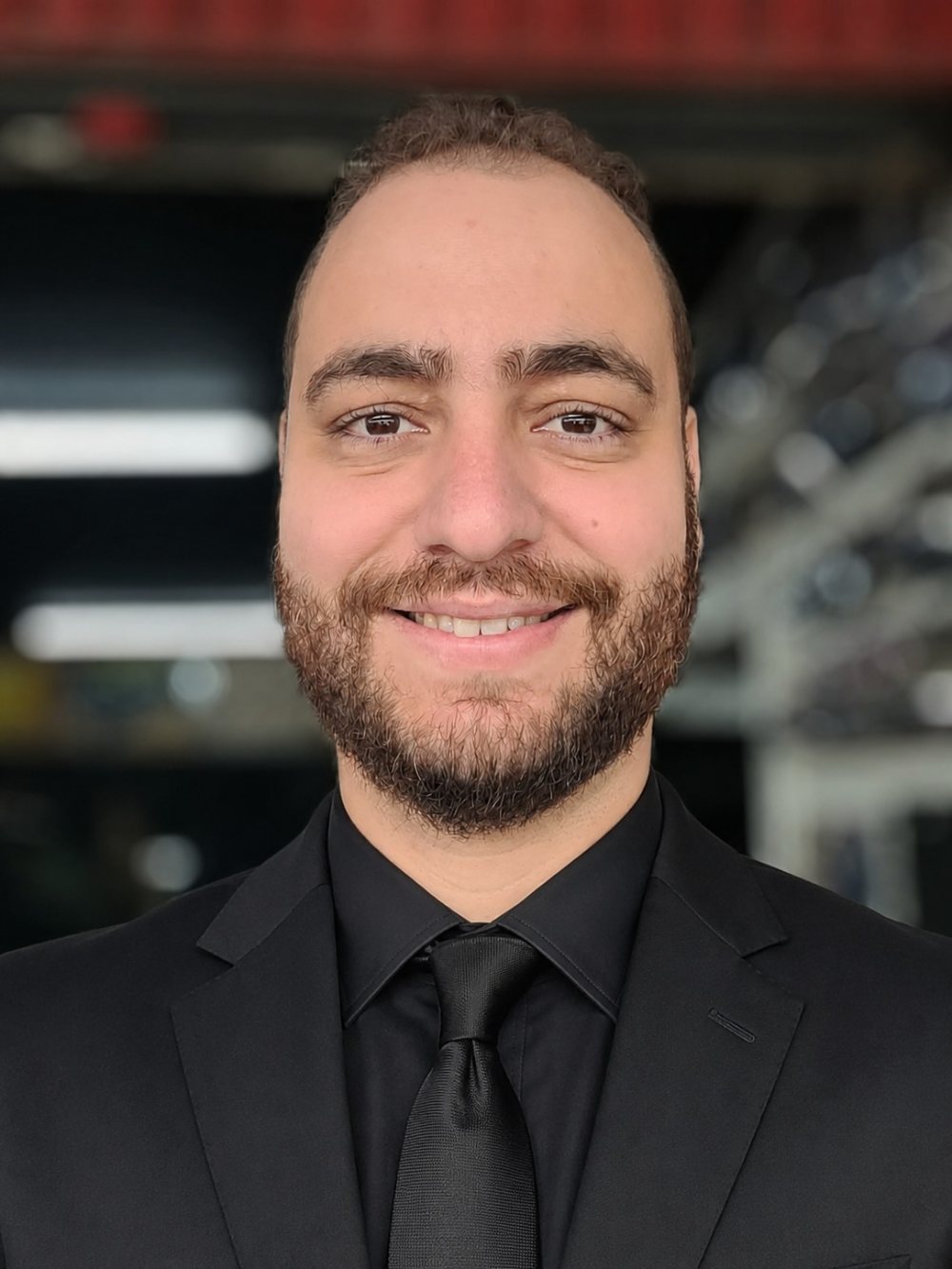 Marco Policarpo, psicanalista, sorrindo, de terno, camisa e gravata pretos